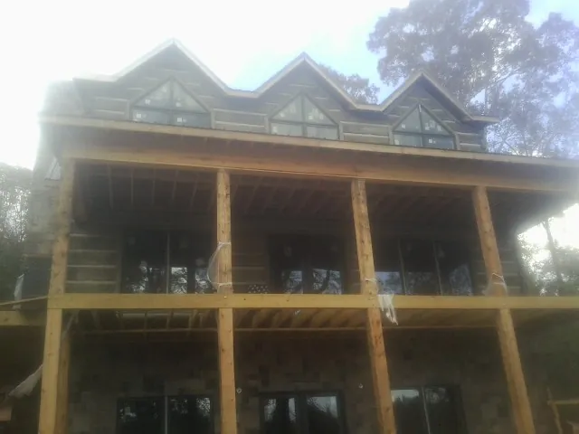 Dormers and porch framing on a large log home under construction — Roof Coating work by our crew in Cumberland